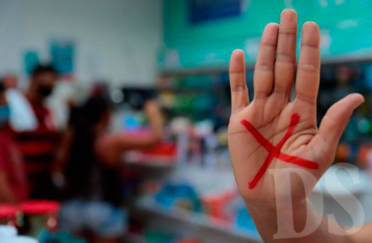 Com um “X” vermelho na mão a vítima sinaliza a violência
